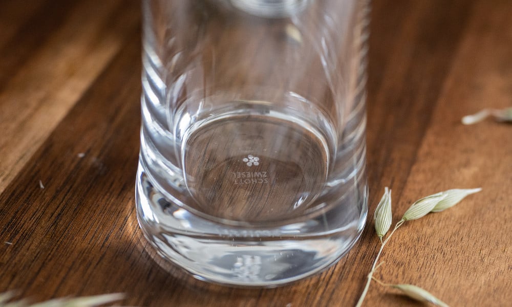 Un vaso vacío está sobre una mesa de madera, rodeado de granos esparcidos.