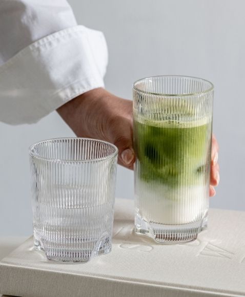Hand greift zu einem Iced Matcha Latte im Allroundglas der Serie Fave von Zwiesel Glas.