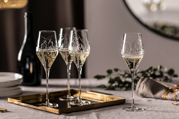 Verres à champagne en forme de tulipe de la série Bar Premium No. 3 de Zwiesel Glas, remplis de champagne et élégamment disposés sur un plateau doré, présentés sur une table dressée de façon festive.