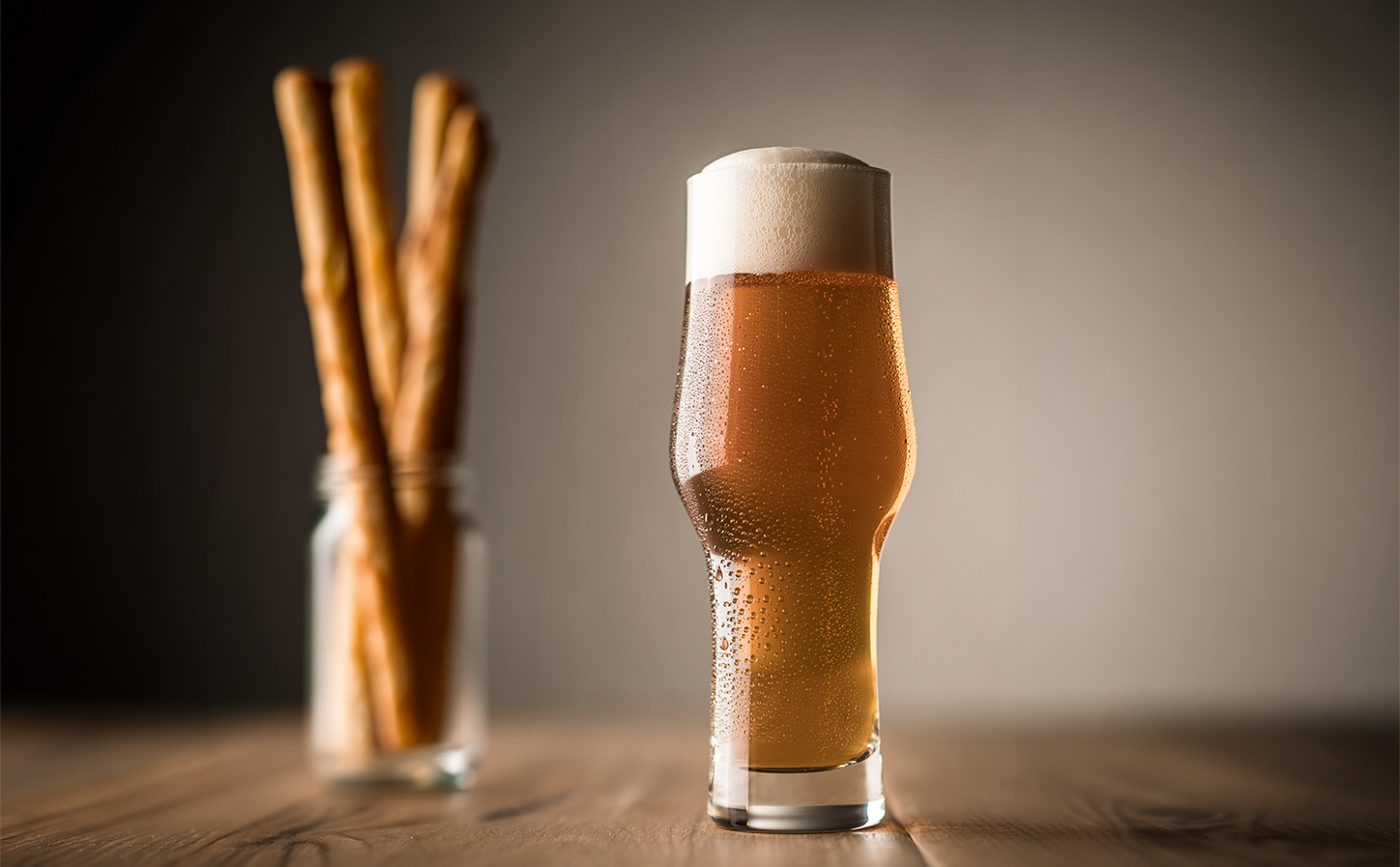 Schott Zwiesel Beer Basic Craft IPA glass filled with India Pale Ale and a creamy foamy head on a wooden table.