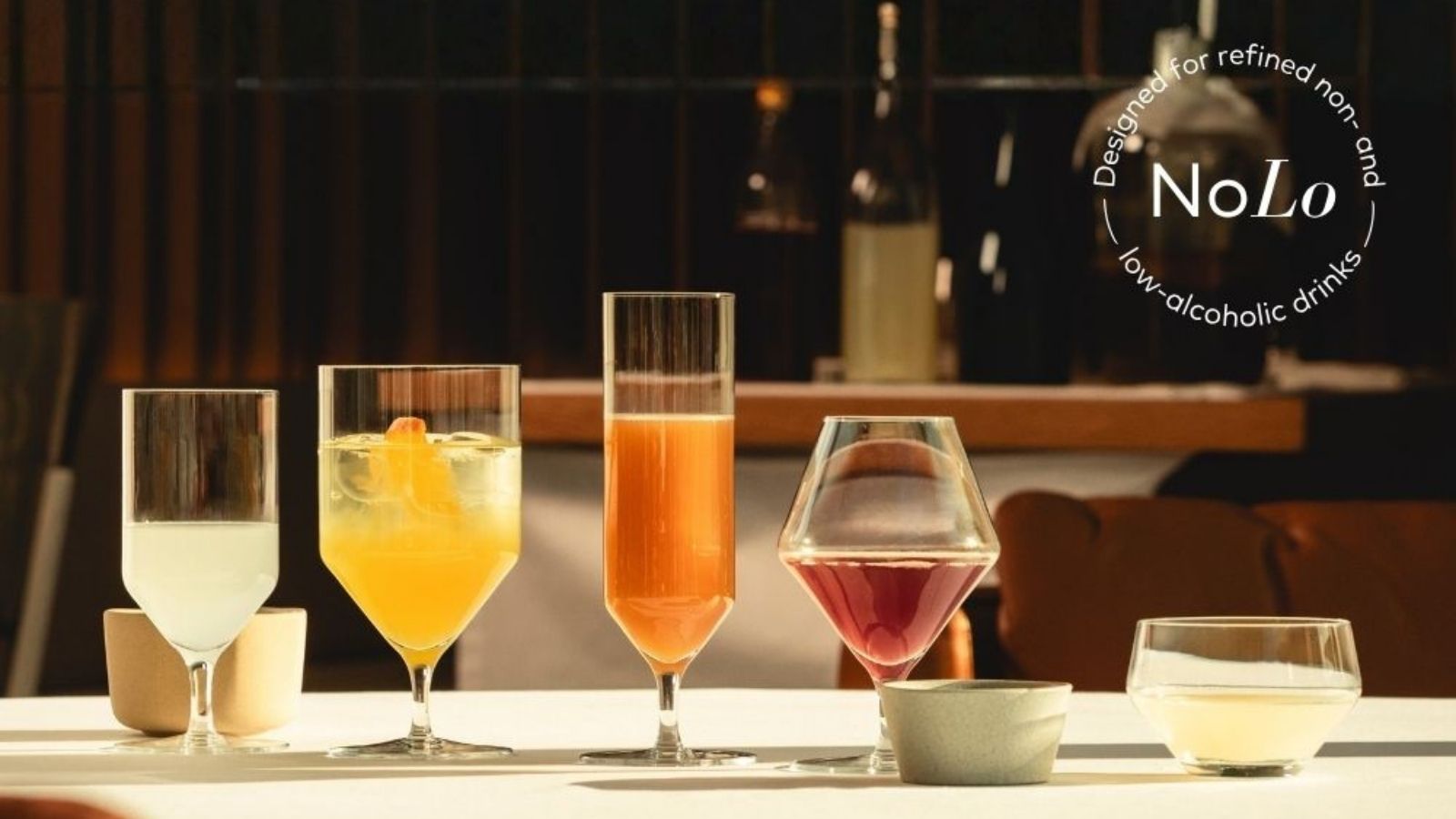 Coloured alcohol-free drinks on a table in a restaurant. The NoLo symbol appears in the upper right corner of the image, indicating that the drinks contain little or no alcohol.