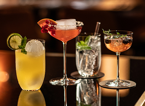 Four bar glasses from the Tone range filled with colourful drinks. Large and small all-purpose glasses, a martini glass and a liqueur glass.
