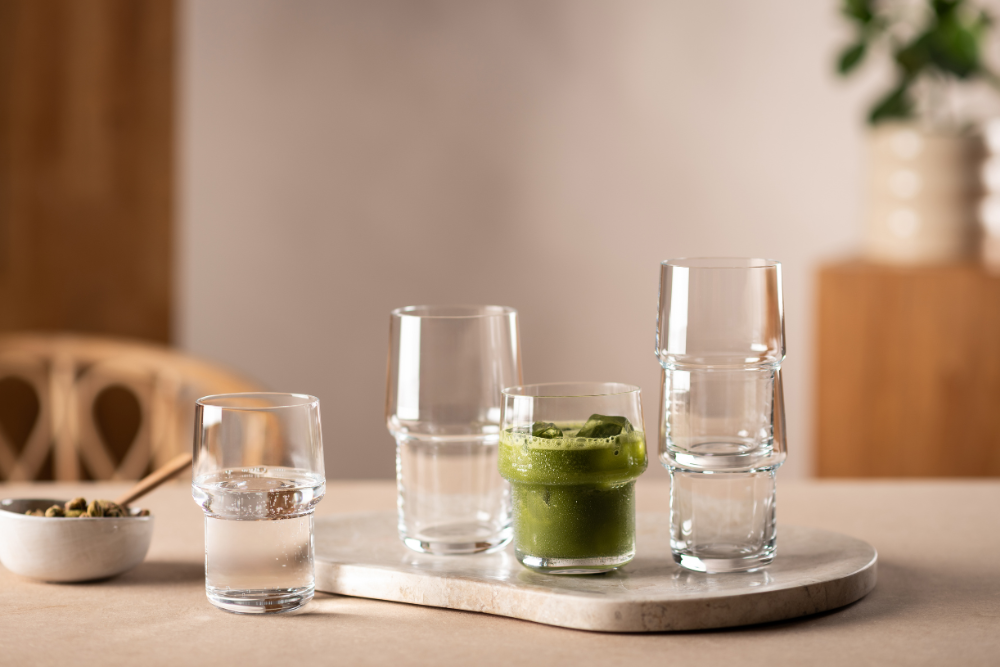 Five Click series drinking glasses on a light-coloured serving board, one of them filled with matcha.