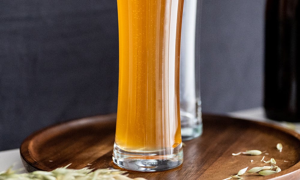 Dos vasos con una bebida de color naranja sobre una bandeja de madera.
