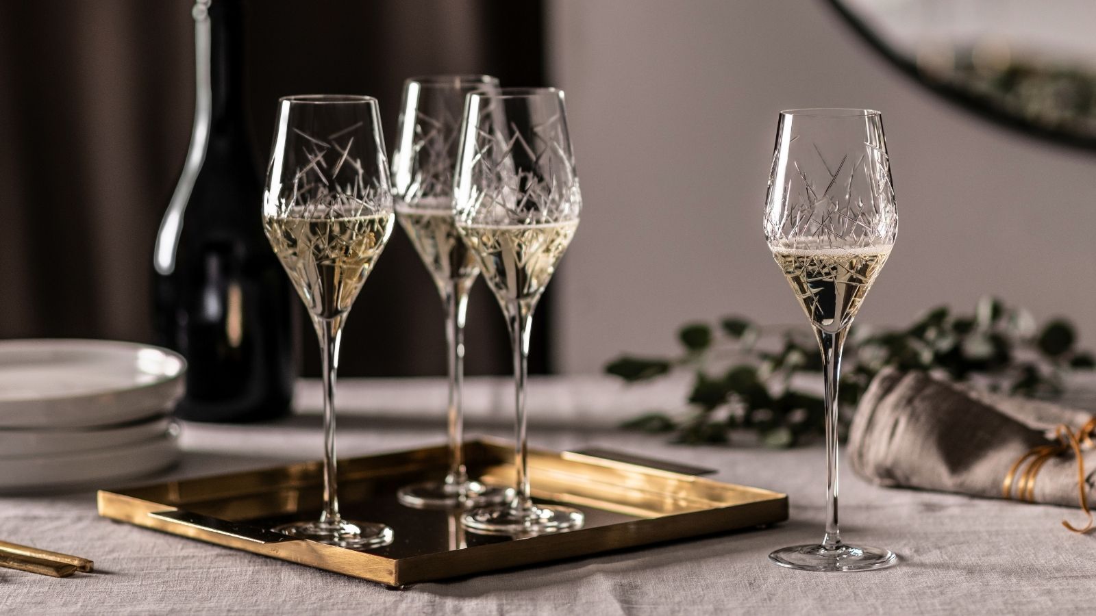 Elegante Sektgläser mit filigranem Dekor auf einem goldfarbenen Tablett, stilvoll arrangiert für einen festlichen Anlass.