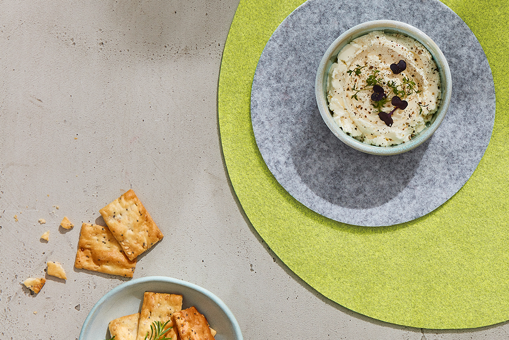 Set de table Fiberixx vert et dessous de verre Fiberixx gris, sur lesquels est posé un bol avec une sauce.