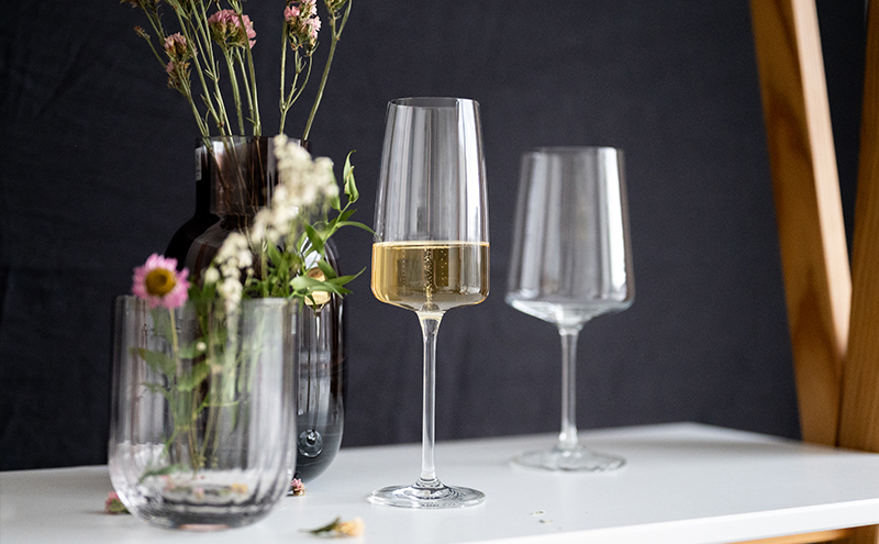 Deux verres à vin sont posés sur la table à côté d'un vase avec des fleurs.