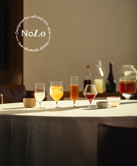 Gläser mit farbigen, alkoholfreien Getränken auf einem Tisch in einem Restaurant. In der linken oberen Ecke des Bildes steht das NoLo-Zeichen. Es weist auf einen niedrigen oder keinen Alkoholgehalt der Drinks hin.