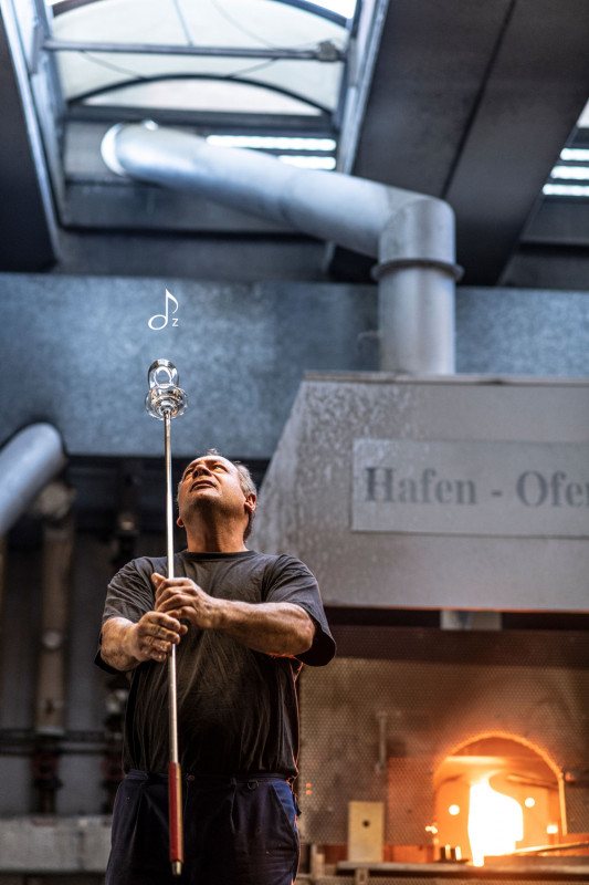 Un soplador de vidrio trabajando frente al horno, moldeando con maestría y simbolizando el arte de la fabricación del vidrio.