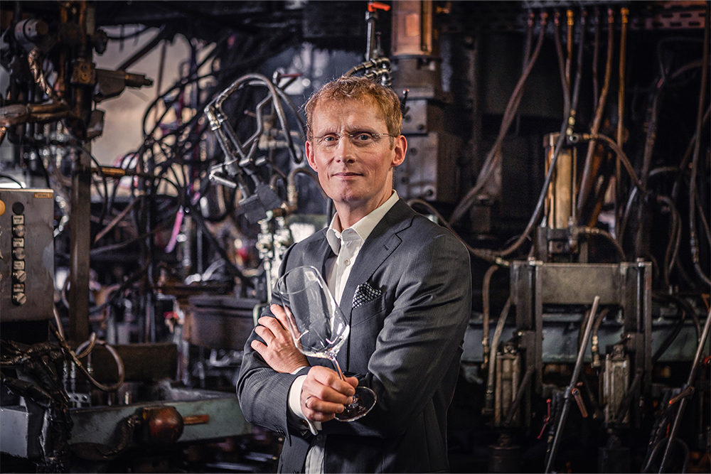 Le professeur Buske devant une machine à verre, symbole de l'innovation et de la précision dans la fabrication du verre.